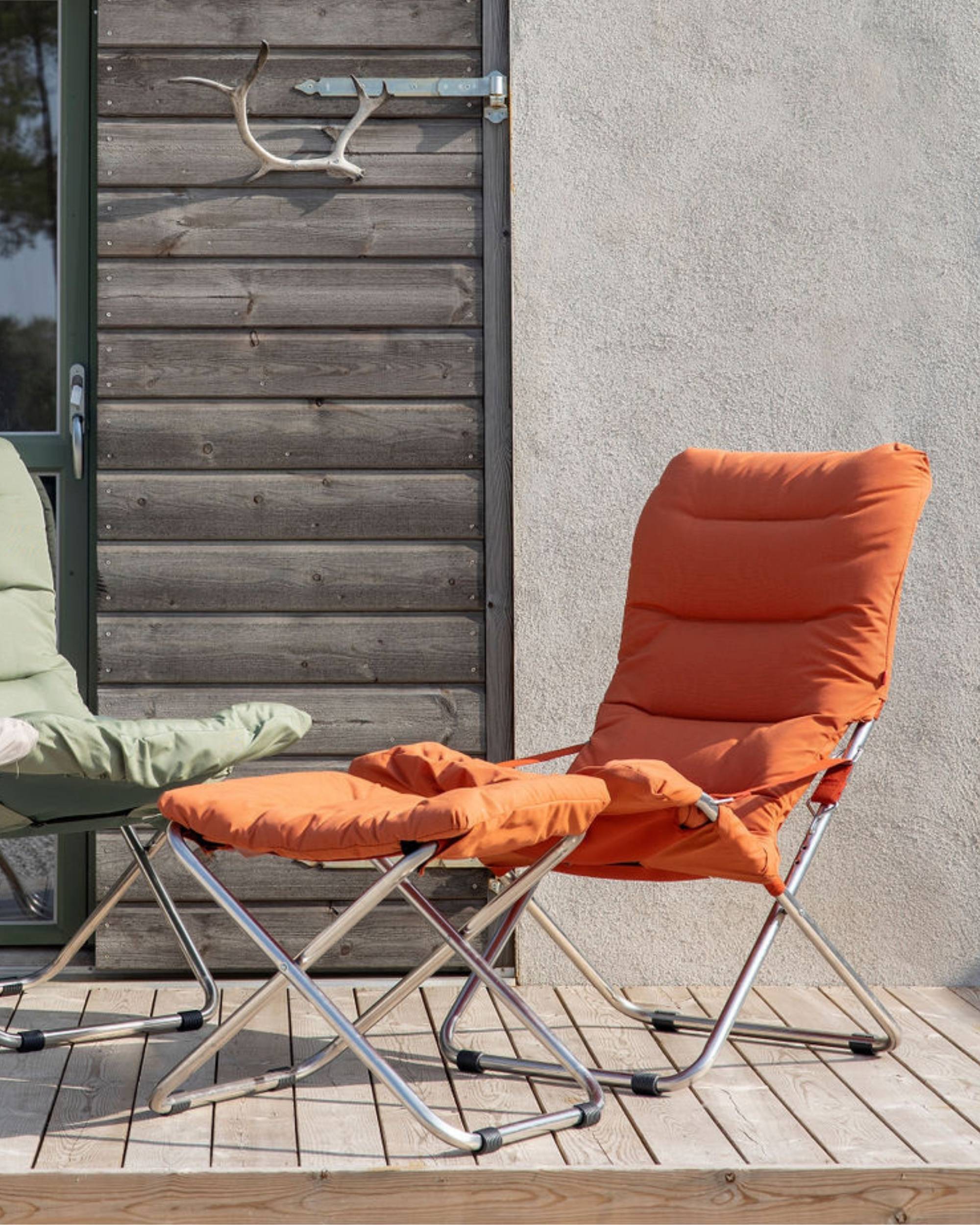 Fiam Chico Soft fotskammel i orange tekstil, med sølvfarget aluminiumsramme på treterrasse.