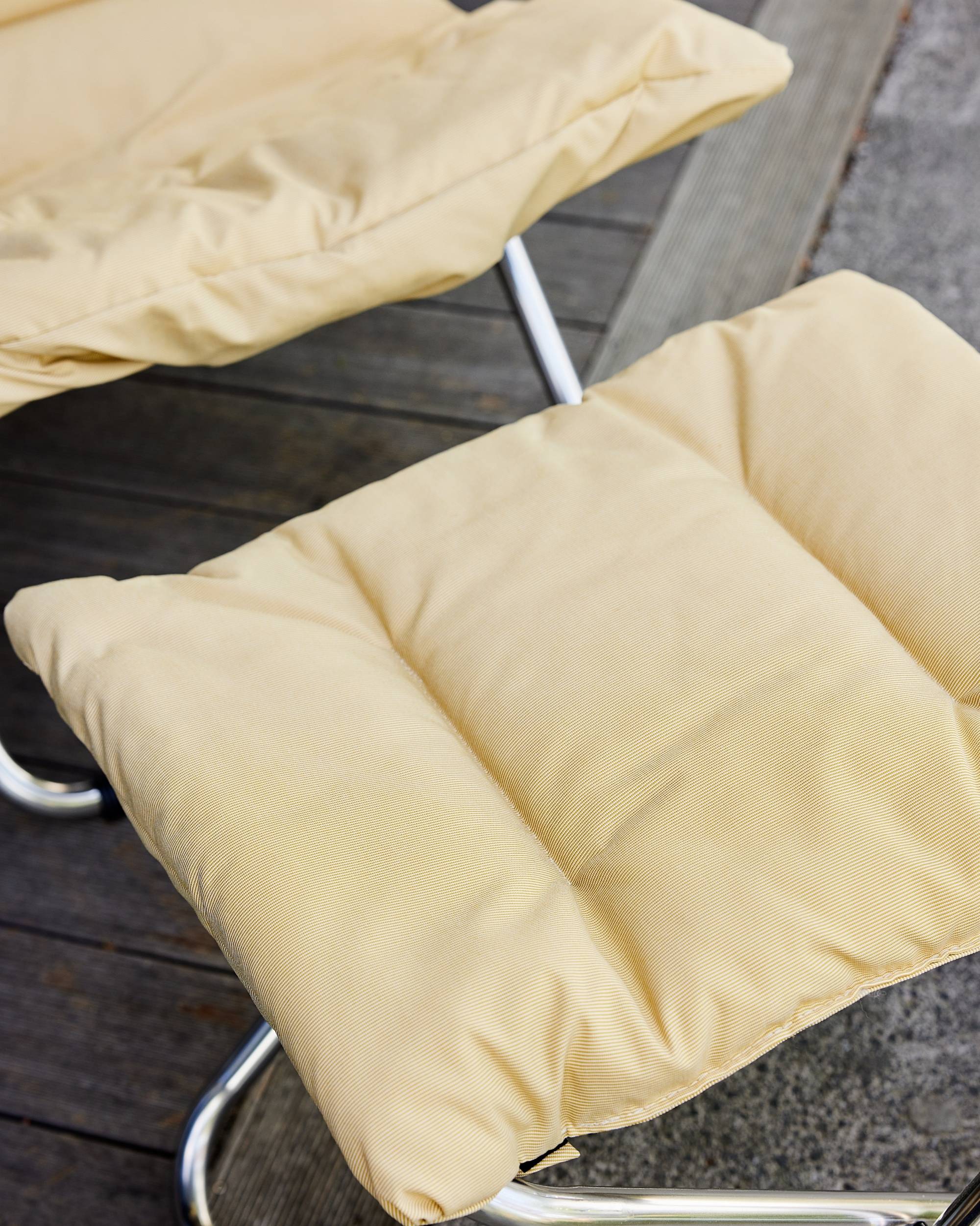 FIAM Chico Soft fotskammel, detalj av gult stripete stofftrekk og skinnende aluminiumsramme.