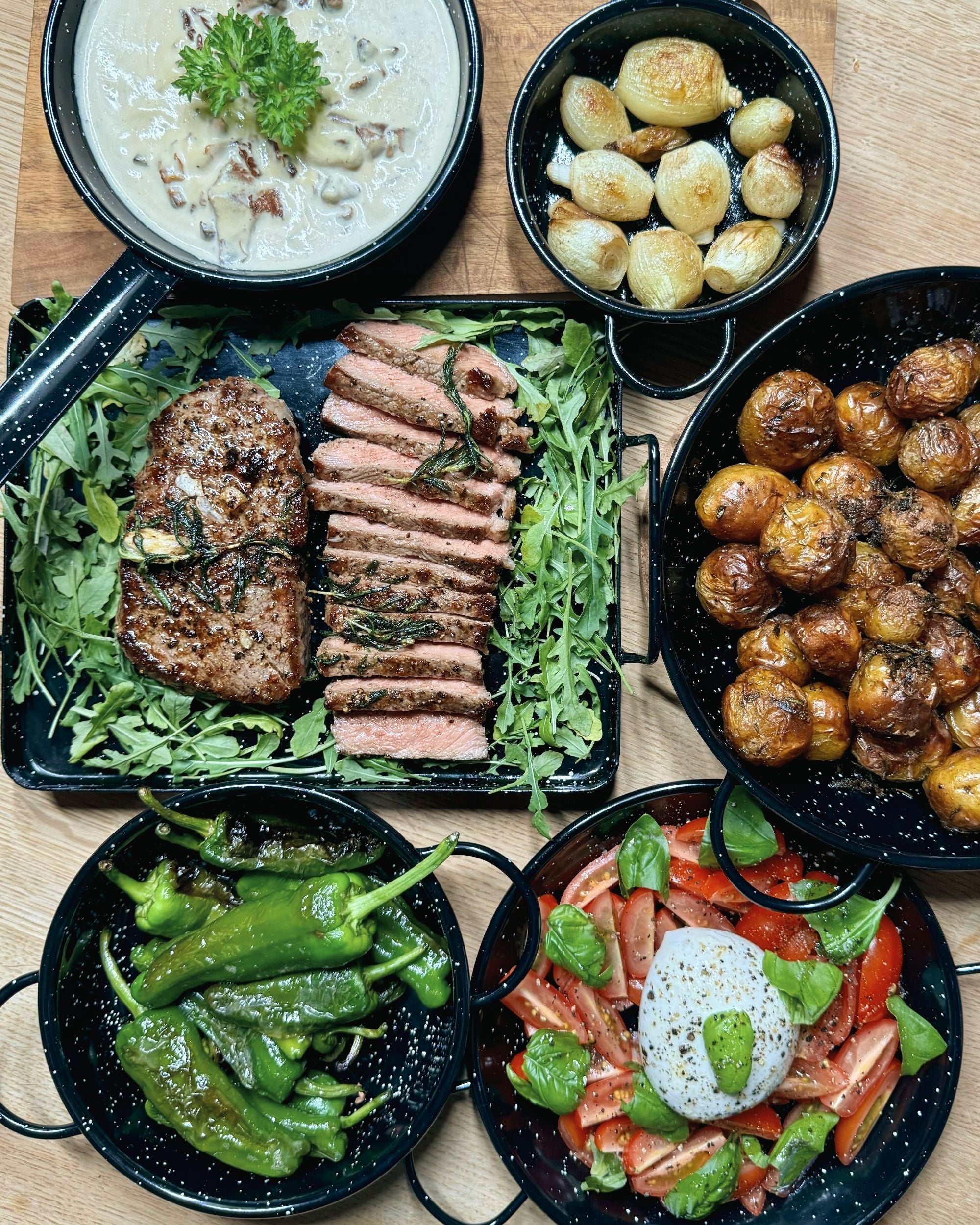 Top view av Vaello emaljert tapasskål med kremet soppsaus, hvit bakgrunn med svarte spetter, og sort kant