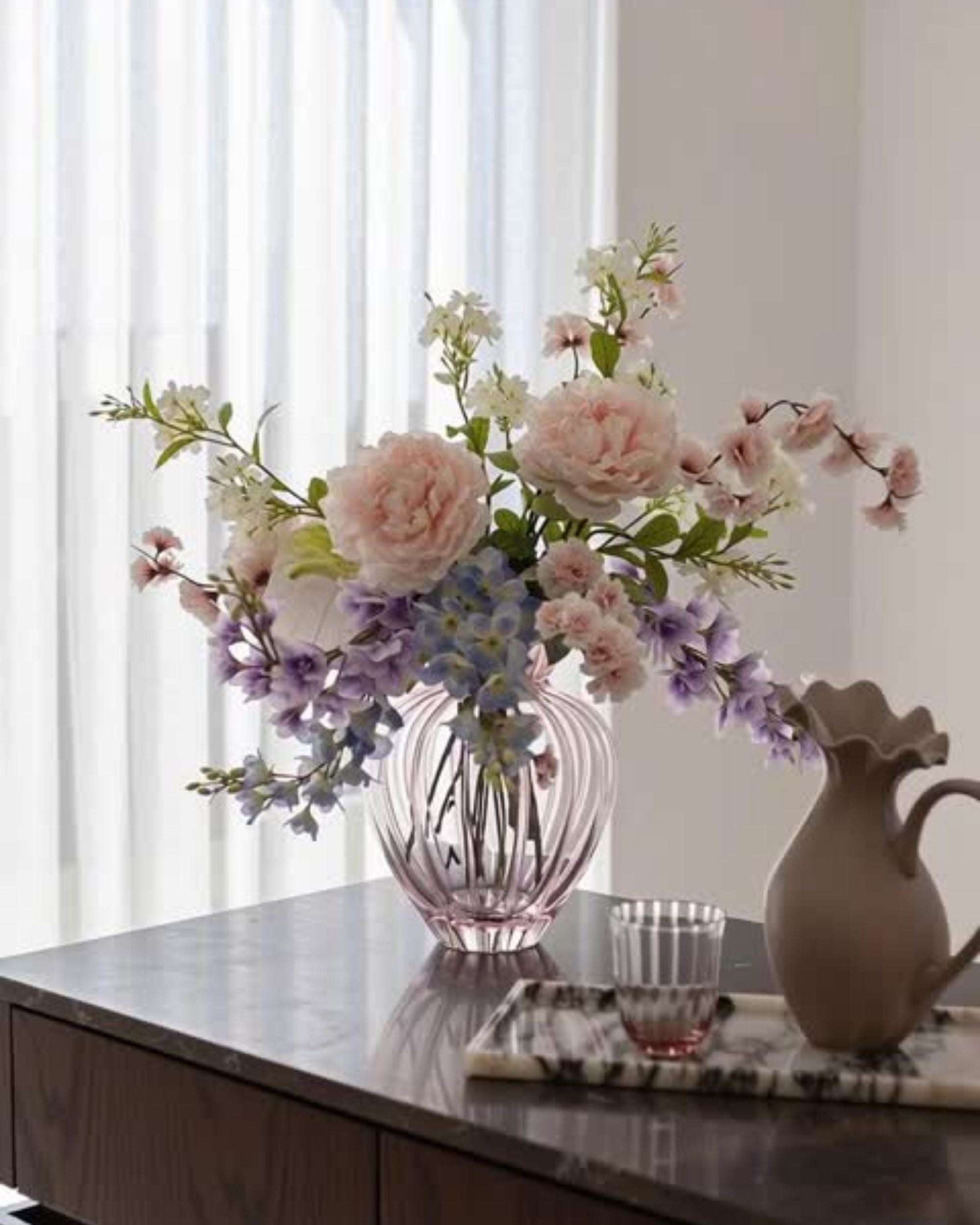 Specktrum Audry Vase Stor i lyserosa rillet glass, fylt med en fyldig blomsterbukett i pastellfarger på bord