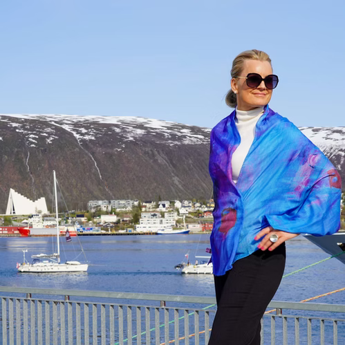 Therese Enger Blurred Line skjerf i blå og lilla med kunsttrykk, båret av kvinne med fjordbakgrunn