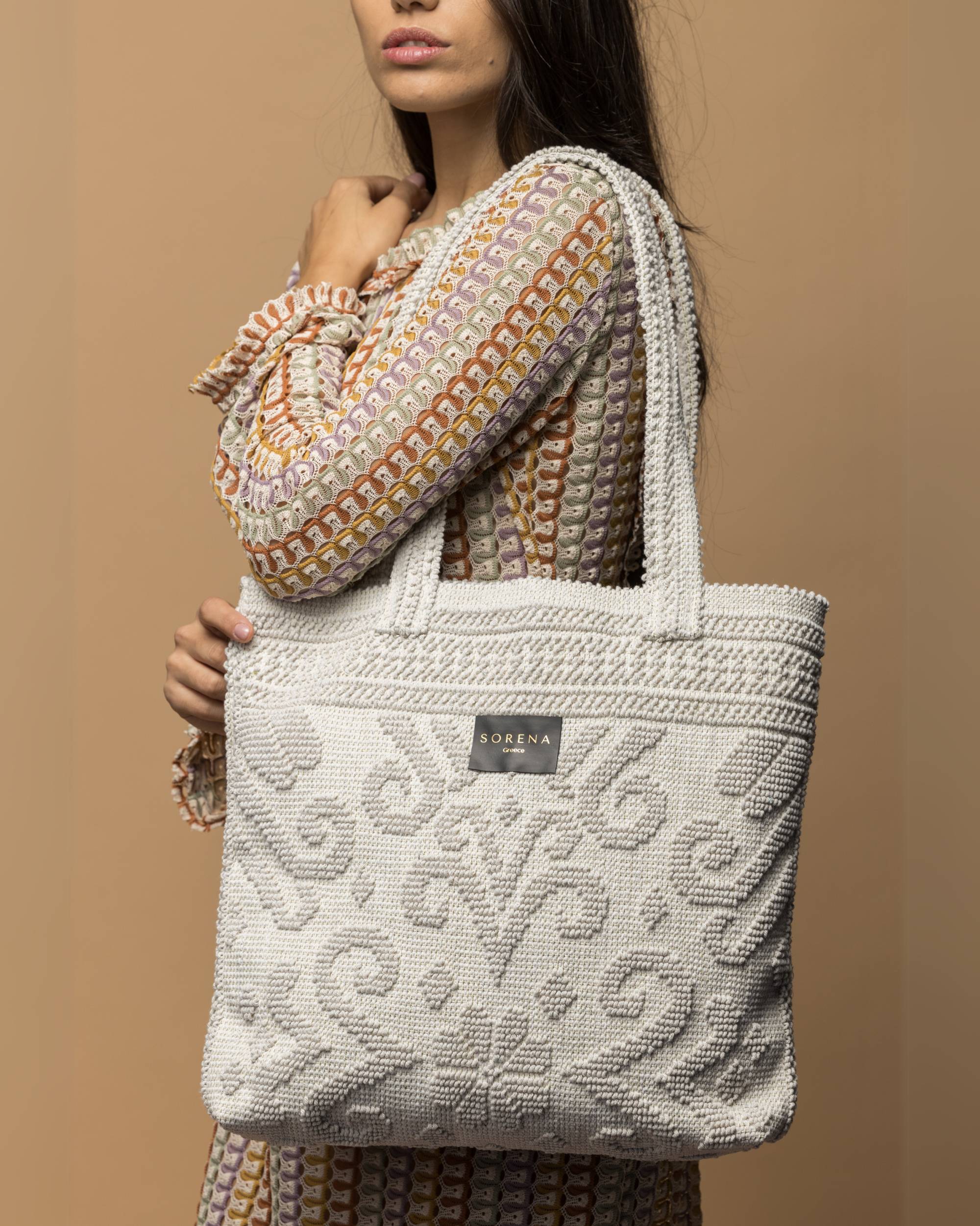 Sorena Chiara BoHo strandveske/toteveske i kremfarget tekstil med norsk inspirert mønster, holdes av kvinne.