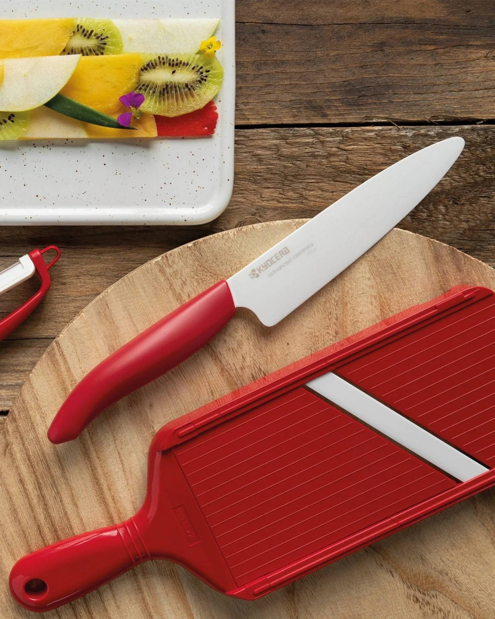 Kyocera mandolin sett fra siden, rød plast, hvitt keramisk blad, detalj av redskap for effektiv kutting