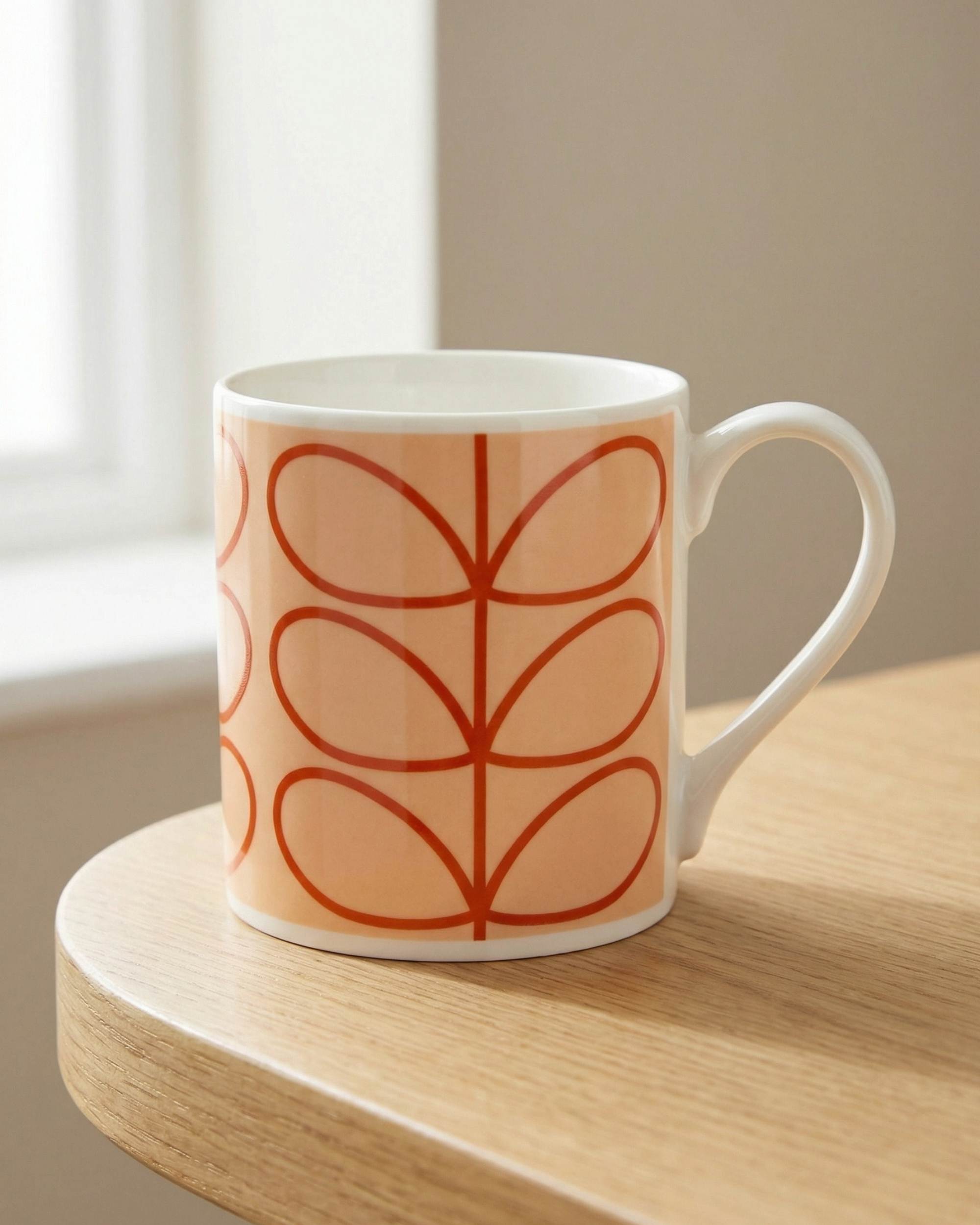 Orla Kiely Linear Stem Tomato kopp i kremfarget porselen, tomatrødt stilkmønster på trebord i sollys