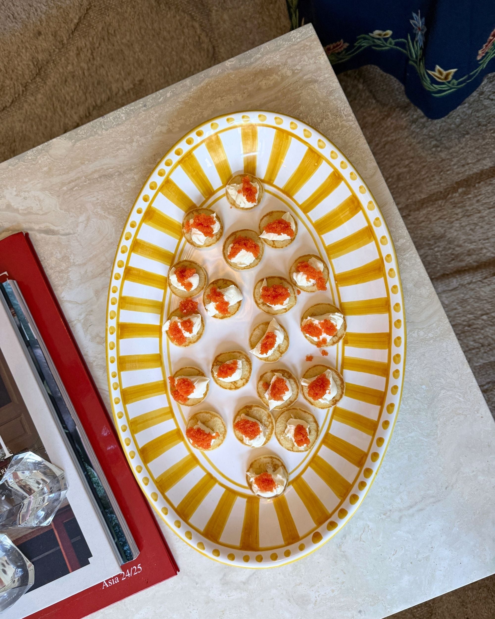 Dipinto Ceramics Linea Ovalt Fat med gult og hvitt stripemønster, fylt med blini og rogn, sett ovenfra