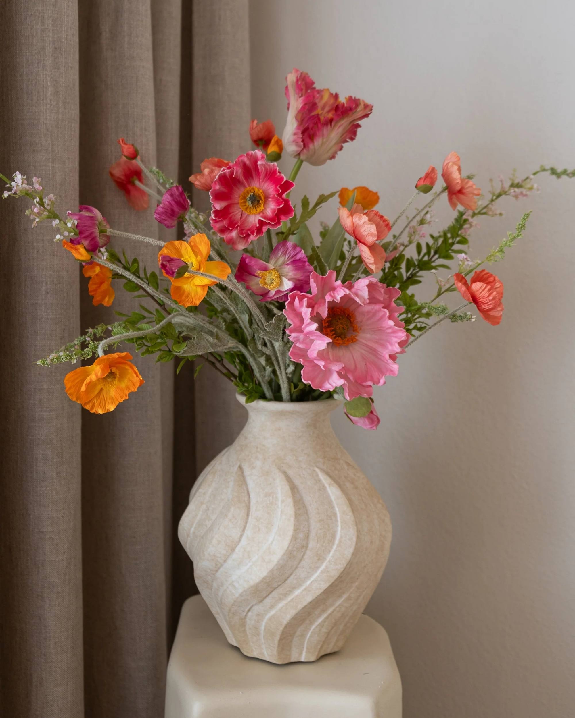 Amarante Pink Lemonade Bukett med 10 naturtro PVC-roser i rosa, orange og lilla nyanser i smal halsvase i beige.