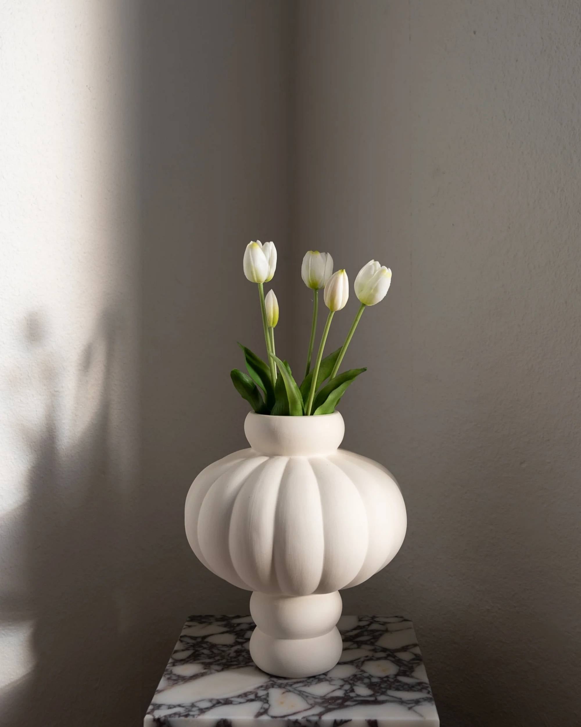 Amarante tulipanbukett med 5 kunstige hvite tulipaner i hvit riflet vase på et marmorbord