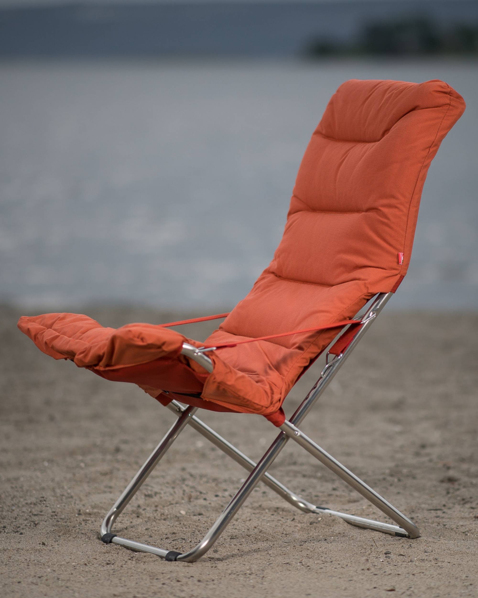 Fiam Fiesta Soft solstol med pute i fargen orange på en strand