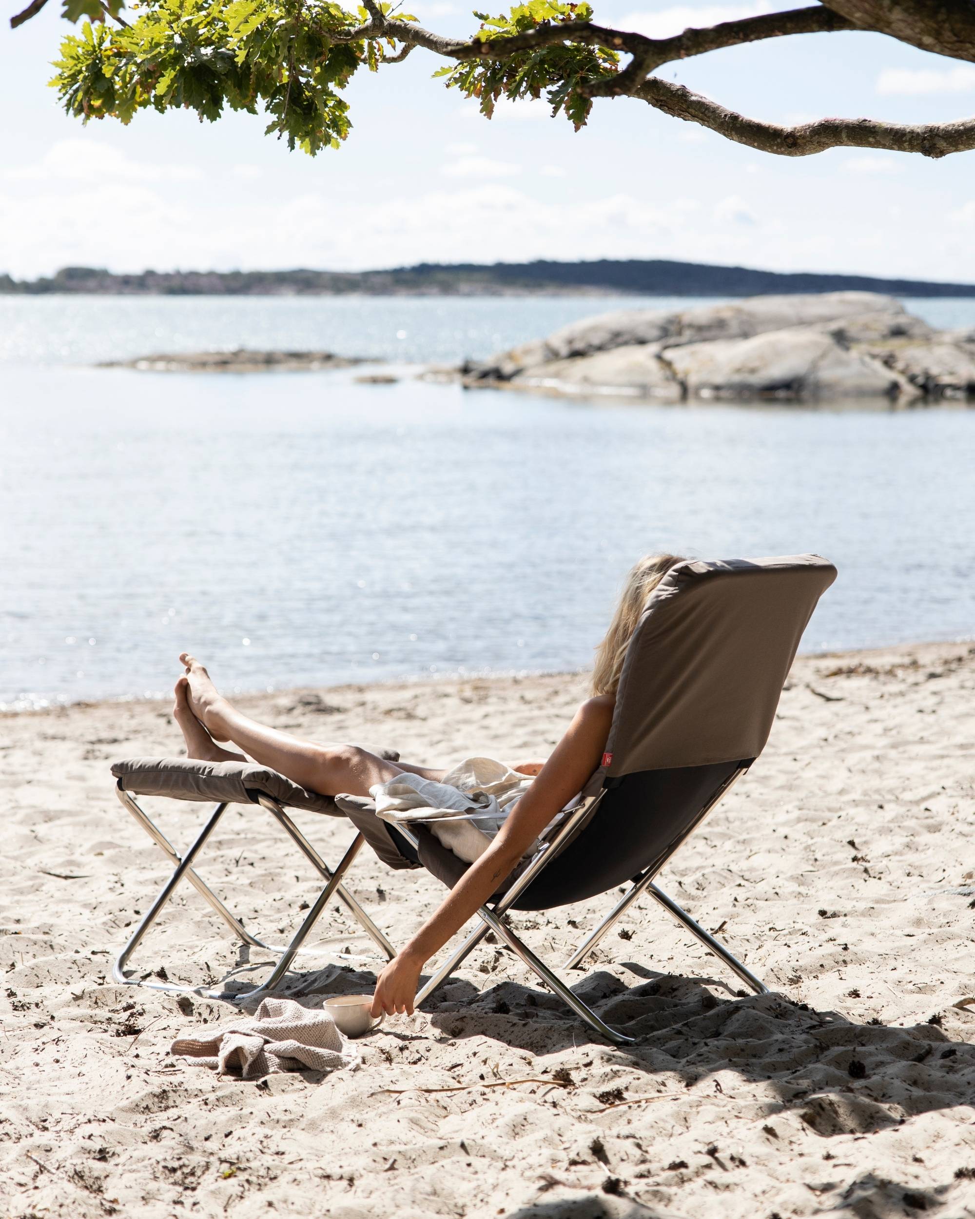 Fiam Fiesta soft solstol og fotskammel med pute i fargen brun på stranden