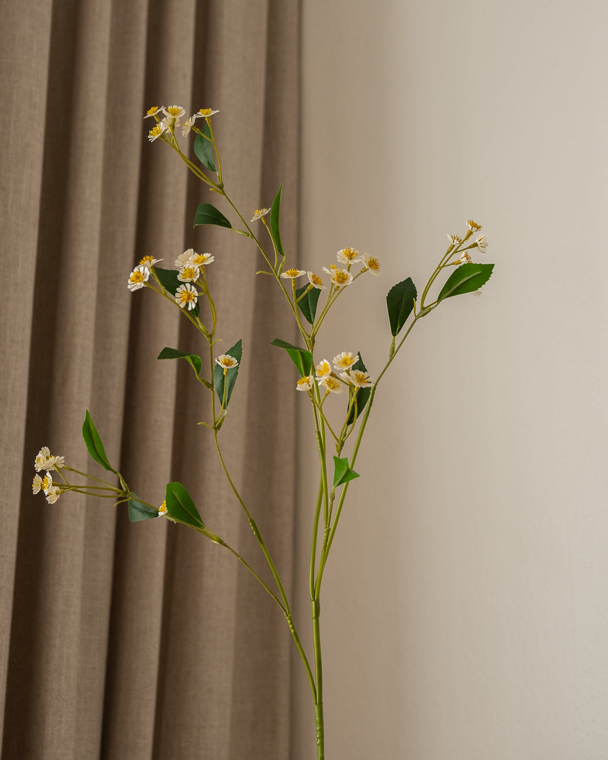 Nærbilde av Amarante Chamomile Daisy kunstig blomst med hvite kronblader og gule sentre, grønne blader.