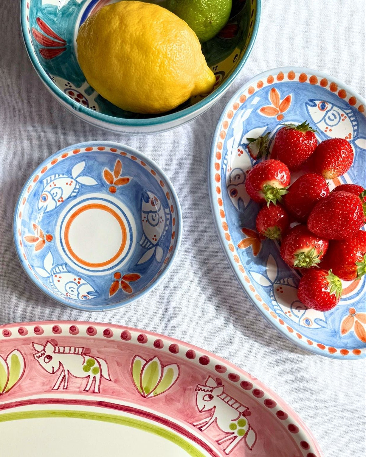 Dipinto Ceramics Amalfi Ovalt Fat 24cm med jordbær, hvit bakgrunn. Blått keramikkfat med fargerikt fiskemotiv og oransje deta