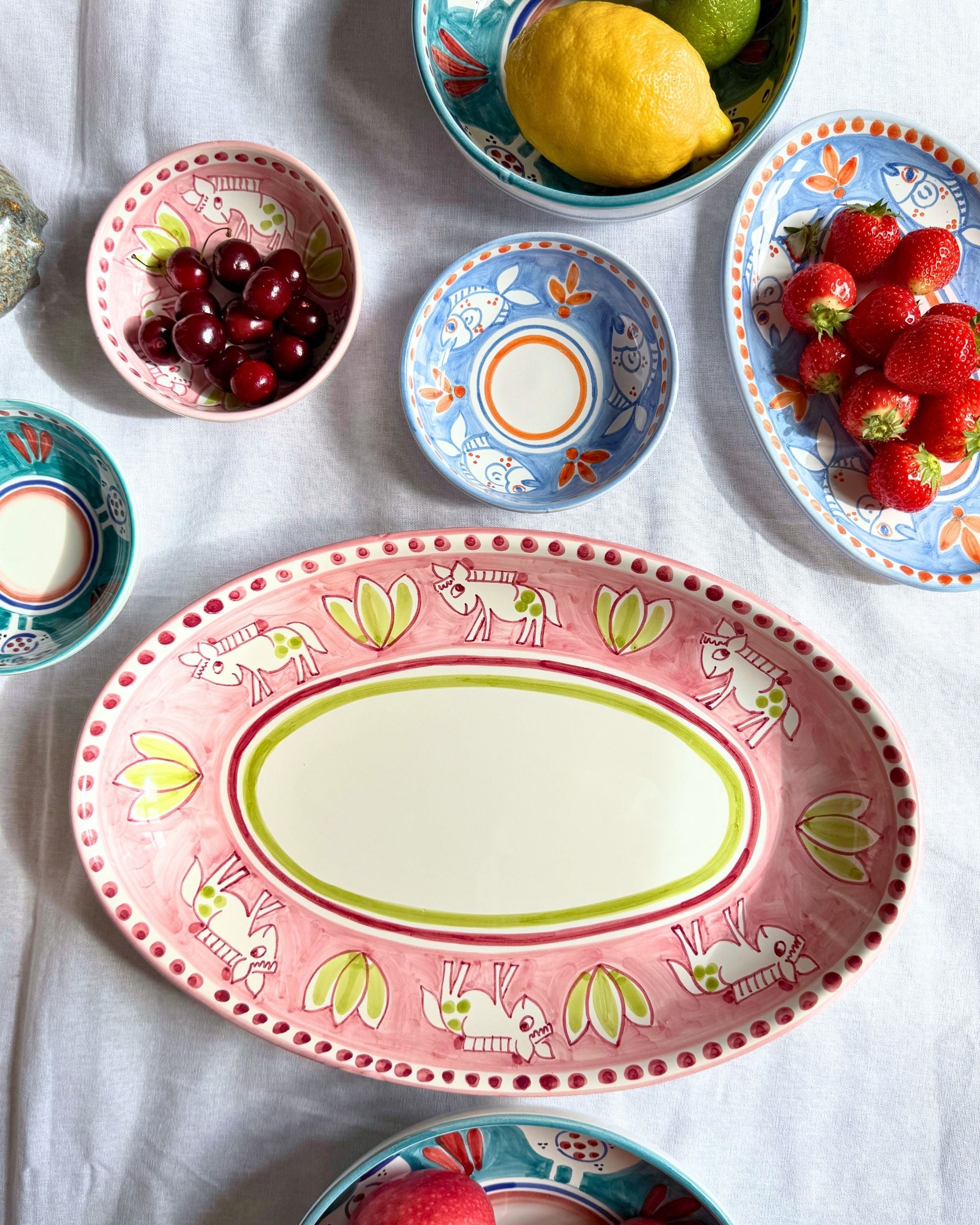 Nærbilde av Dipinto Ceramics Amalfi Ovalt Fat med rosa kant, fargerikt håndmalt mønster med esler og blomster.