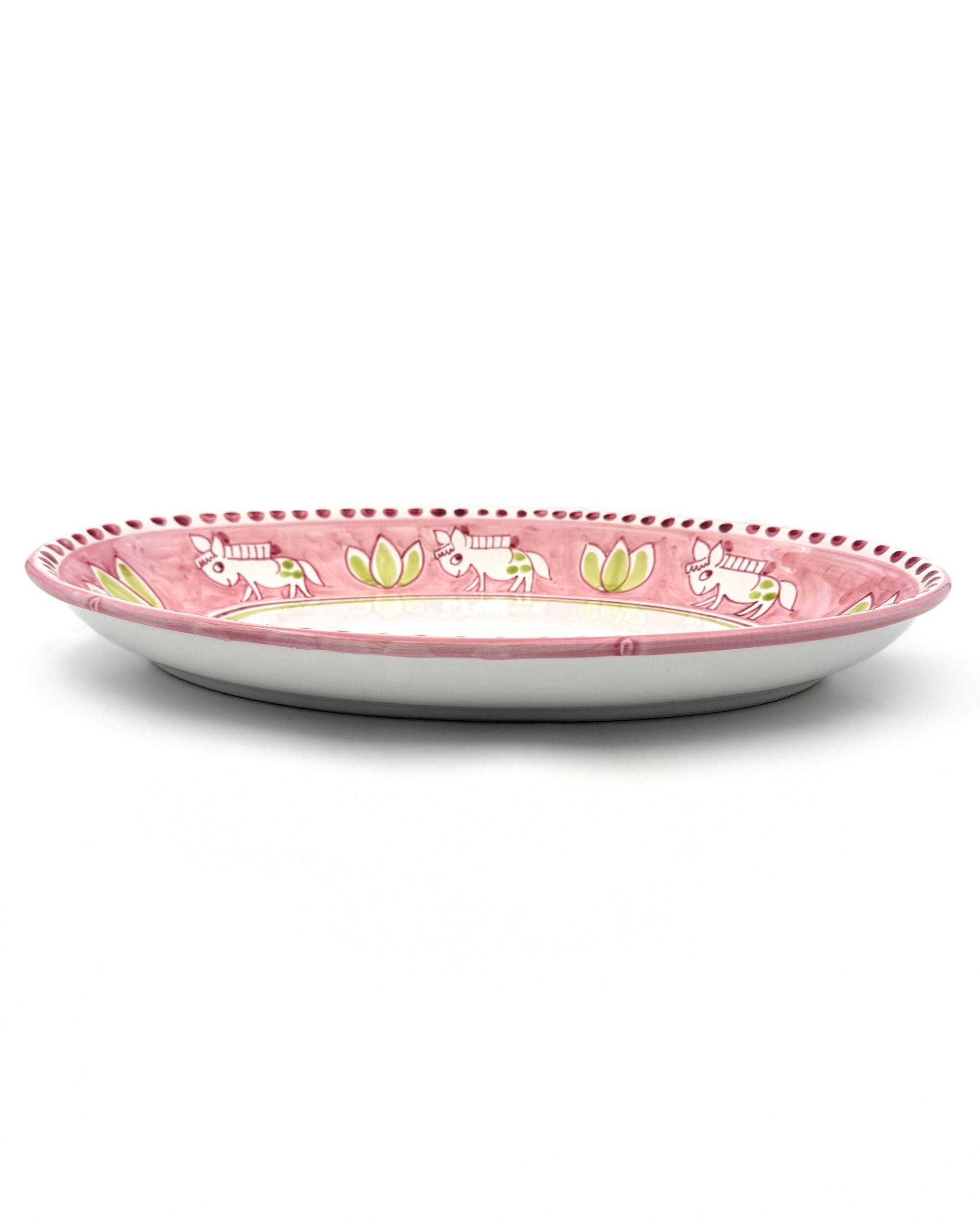 Sidebilde av ovalt Amalfi fat i rosa keramikk. Håndmalte hvite esler og grønne blader, prikkete kant.