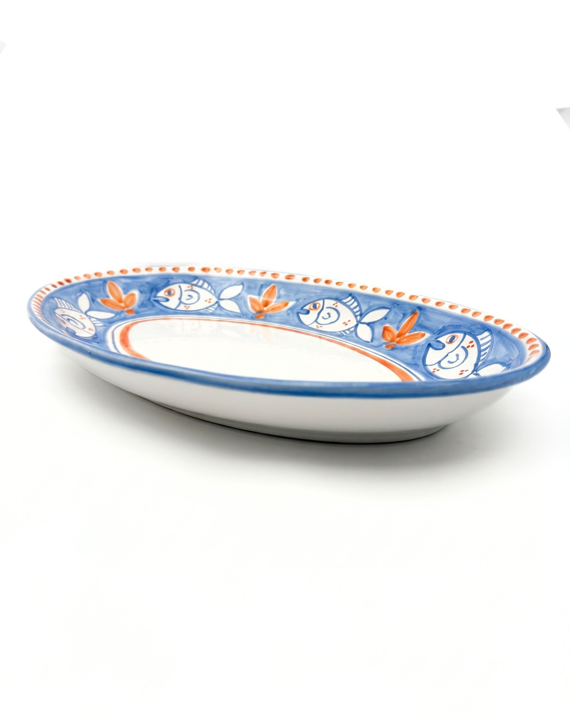 Dipinto Ceramics Amalfi Ovalt Fat 40cm, detaljbilde. Håndmalt mønster med blå fisk og oransje blader på hvit keramikk.