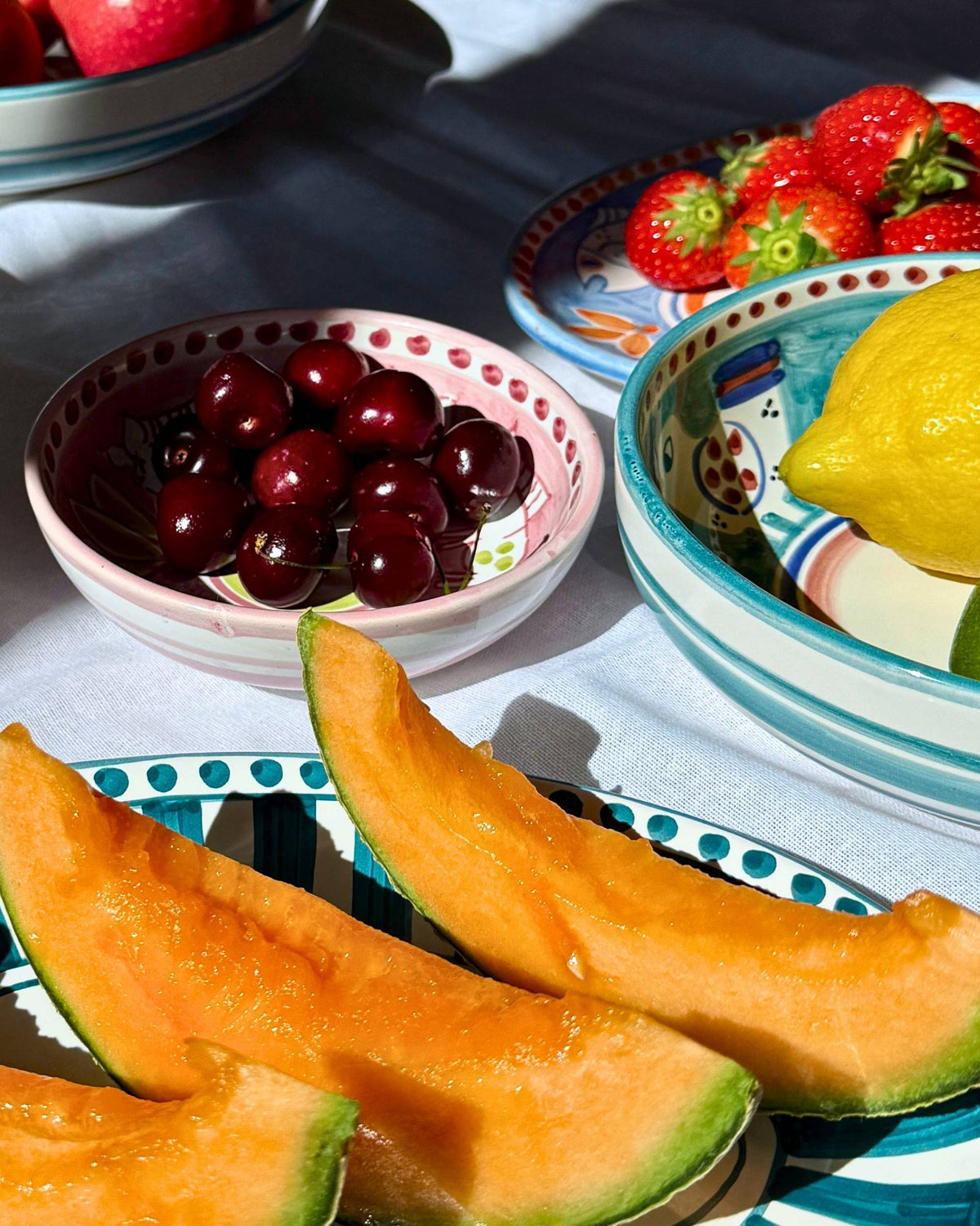 Dipinto Ceramics Amalfi liten bolle i lyseblå og hvit keramikk, fylt med en sitron og en lime i sollys