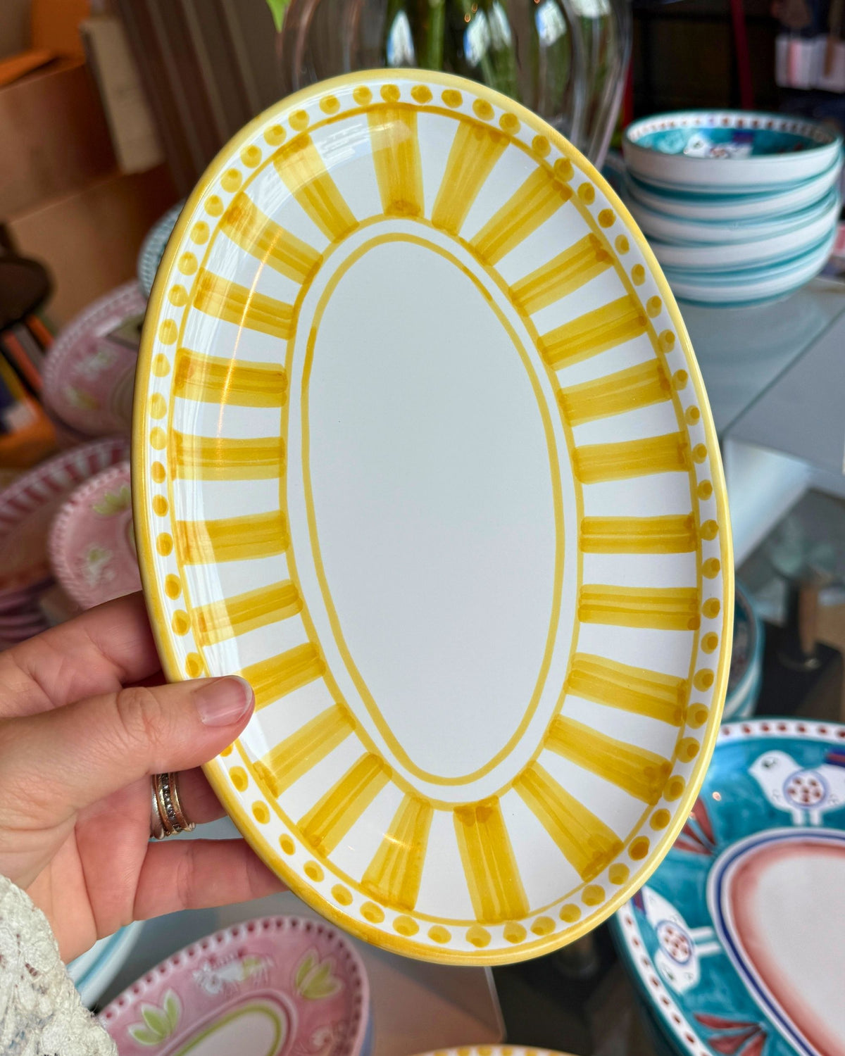 Håndholdt Dipinto Linea Ovalt Fat 24cm i keramikk, gult og hvitt solstrålemønster med prikker.