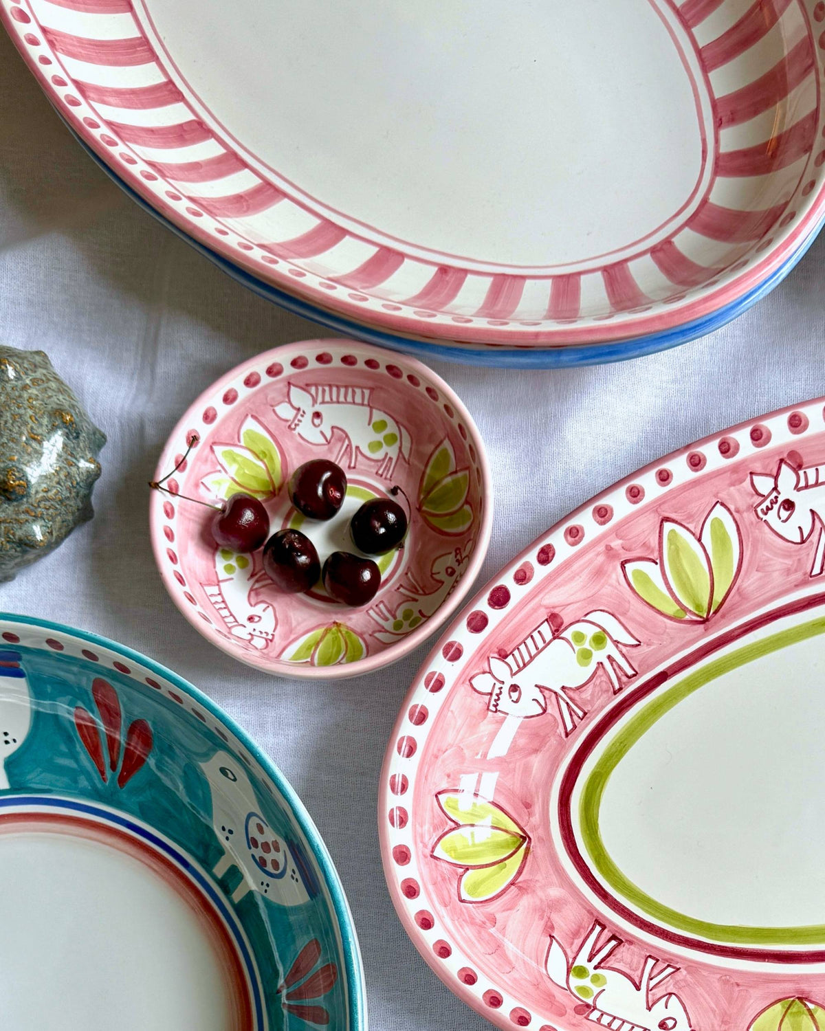 Dipinto Ceramics Amalfi Liten Bolle, rosa keramikk med hvite hestemotiv og grønne blader, kirsebær oppi.