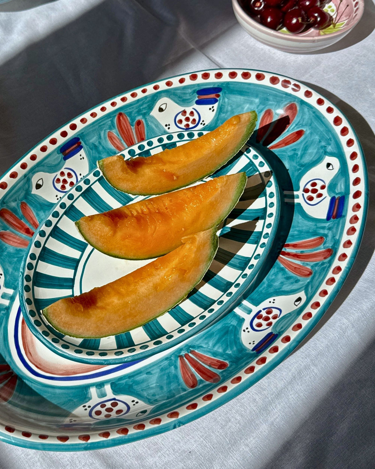 Detalj av Dipinto Ceramics Linea Ovalt Fat med håndmalt mønster av fugl og striper, i turkis og rødt