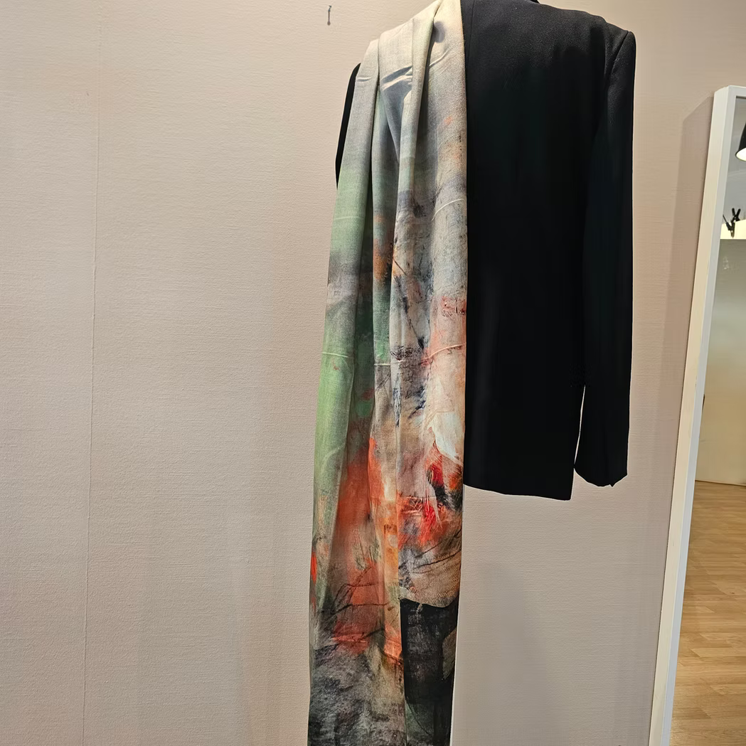 Dovrefjell Kunstskjerf fra Therese Enger kunstprint, grønne og oransje toner, drapert over svart blazer