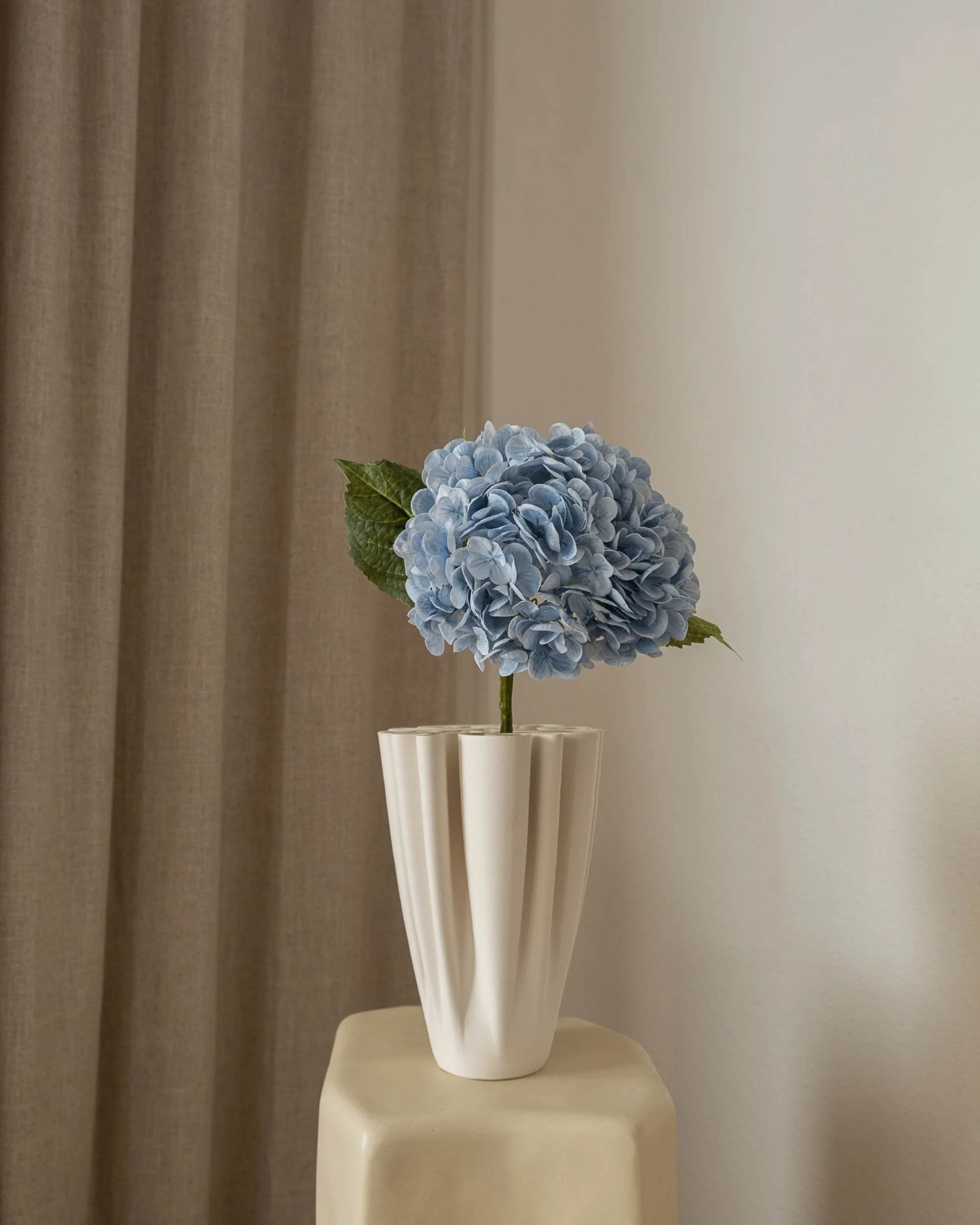 Naturtro Amarante Hortensia blomst i blå, med grønt blad, i foldet hvit vase, detaljbilde