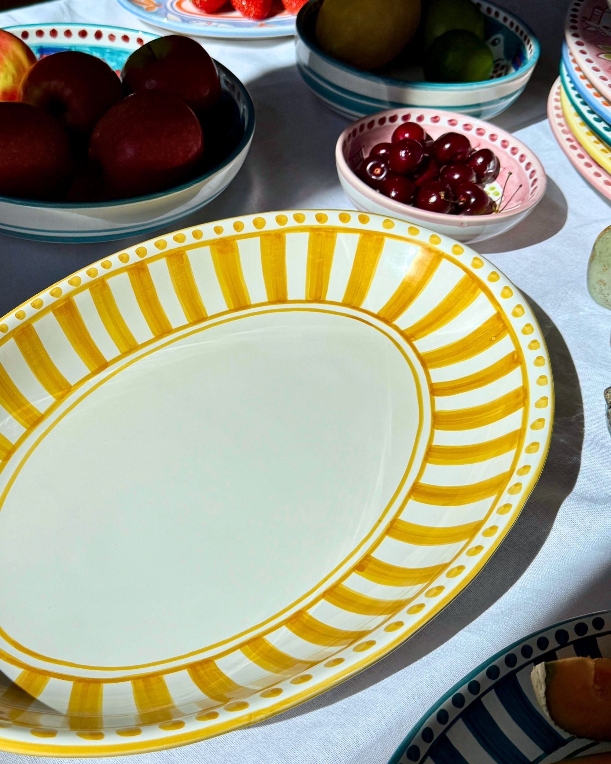 Dipinto Linea Ovalt Fat 40cm, håndmalt keramikk med gule striper, ovale prikker, på hvit duk