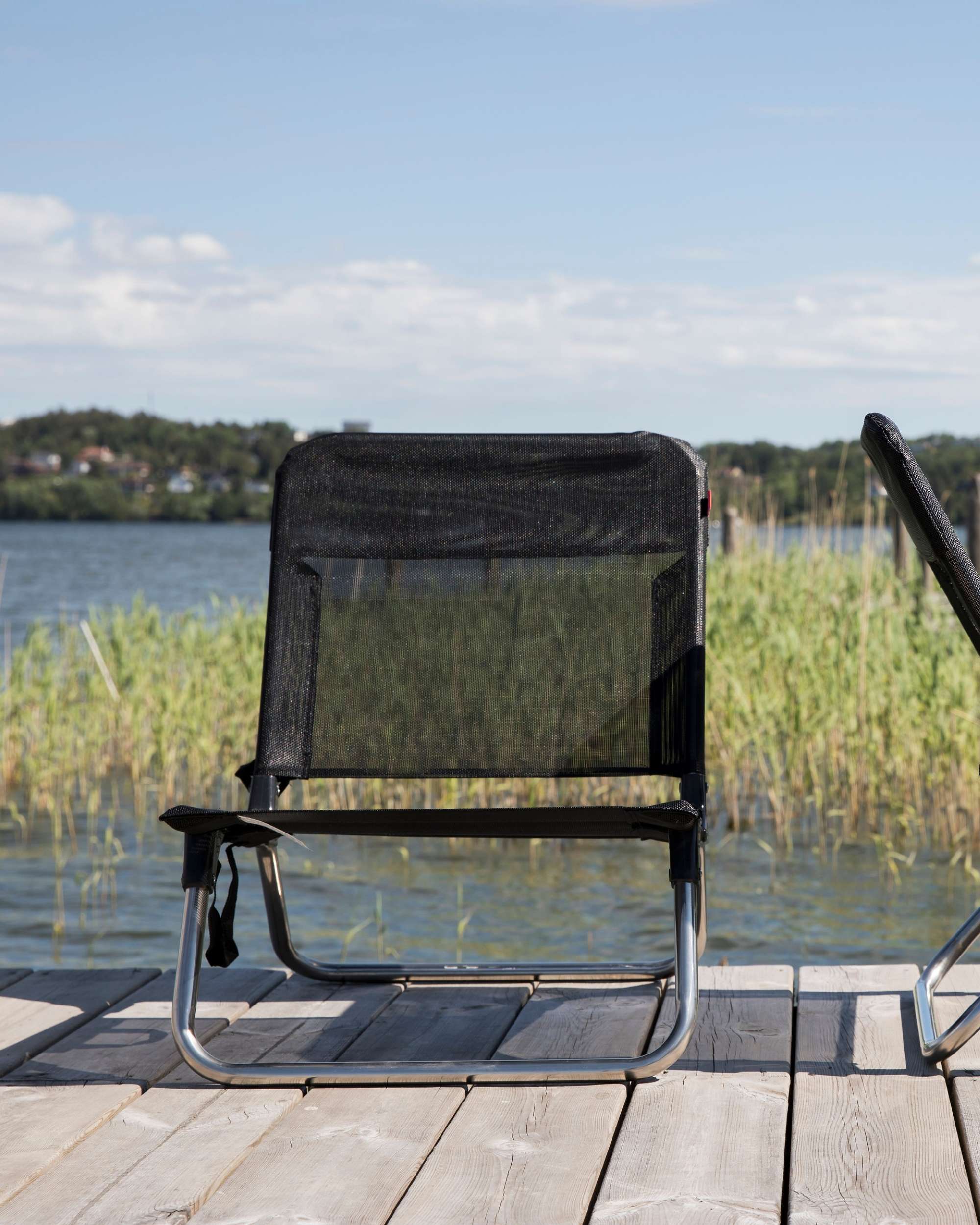 Fiam Strandstol Quick, detalj av svart tekstilen og aluminiumsramme på brygge med vann i bakgrunnen