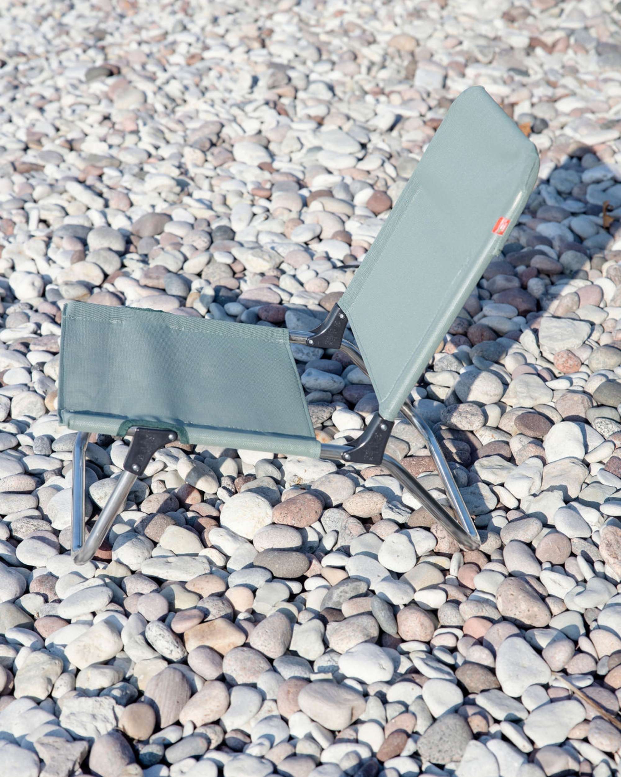 FIAM Quick strandstol i mintgrønn tekstil og aluminium, sammenfoldet og sett bakfra på småstein