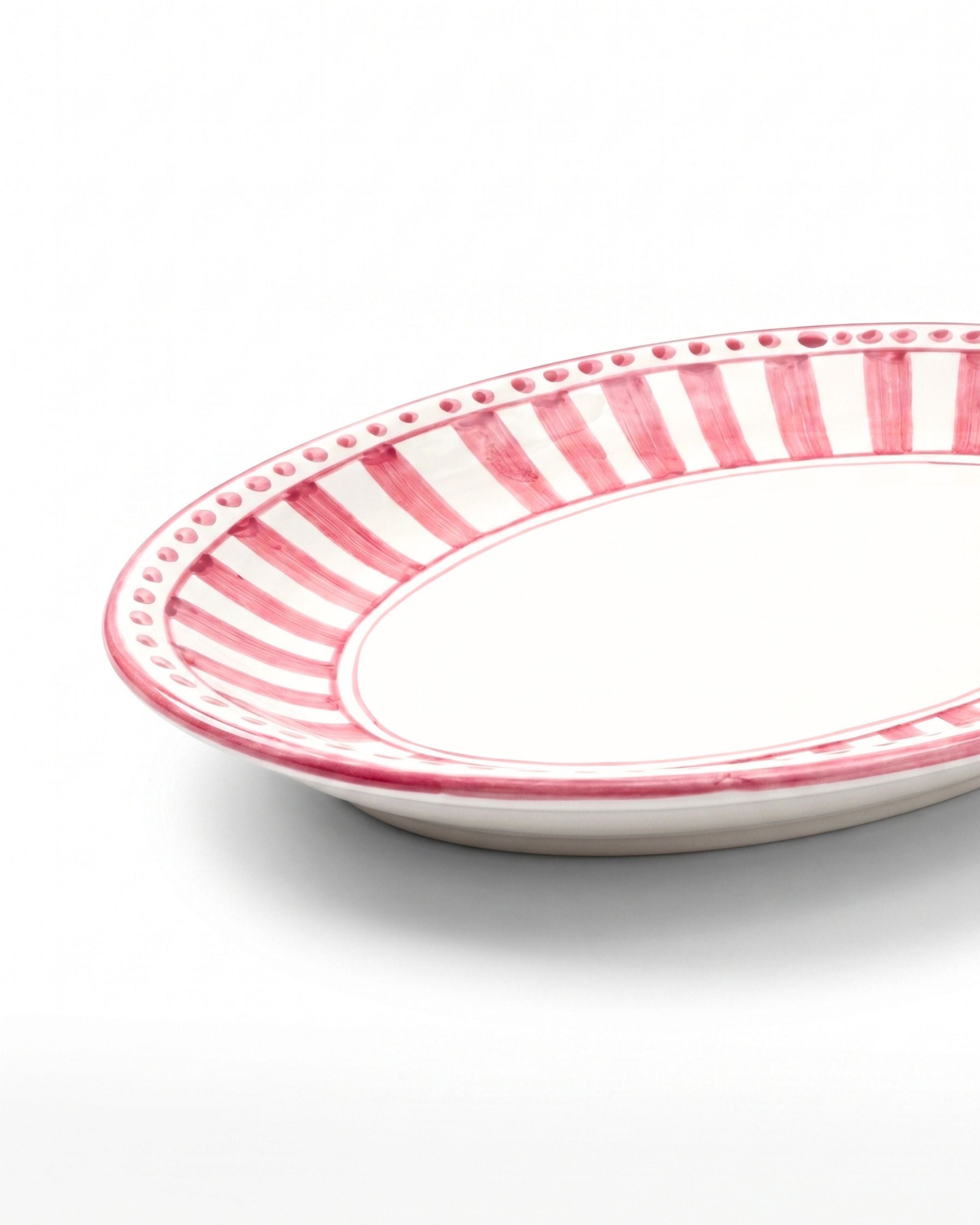 Nærbilde av Dipinto Ceramics Linea Ovalt Fat med kant i hvitt og håndmalt stripemønster i rosa nyanser, detaljer av perlebord