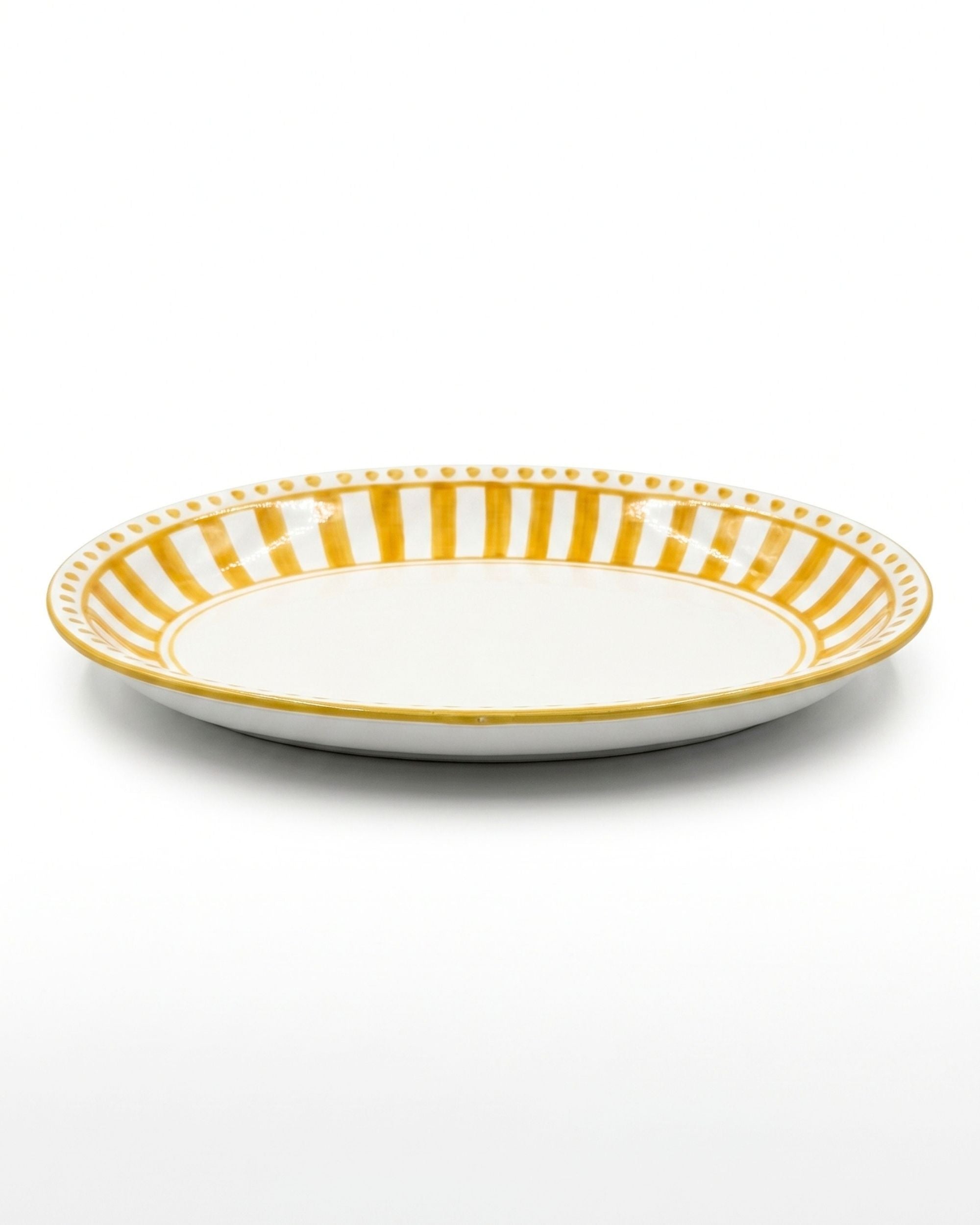 Dipinto Ceramics Linea Ovalt serveringsfat, håndmalt keramikk, med gult stripemønster og prikkete bord rundt kanten.
