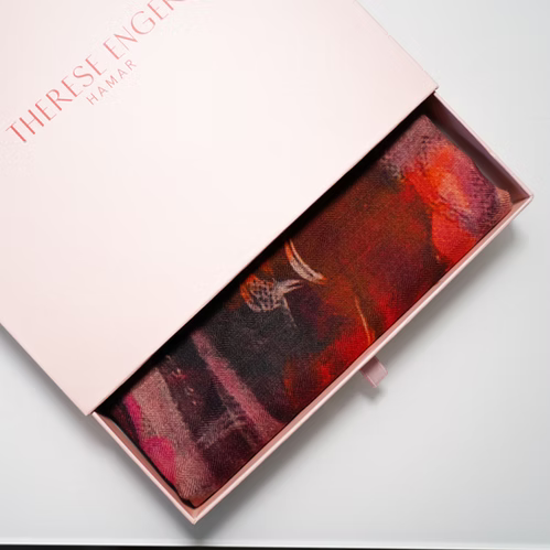Movement skjerf fra Therese Enger med abstrakt kunstprint, delvis synlig i en åpen rosa gaveeske
